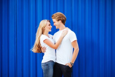 mavi bir arka plan üzerinde gülümseyen genç bir çift. Yaşam tarzı kavramı