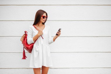 Beautuful esmer kız beyaz arka plan karşı sokağında smartphone ile.