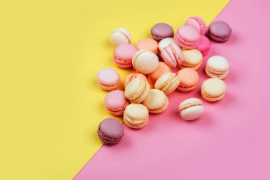 Lezzetli macarons sarı - pembe bir arka plan üzerinde çapraz iki üçgen içine bölünmüş