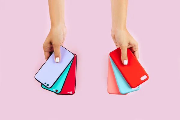 Mãos Segurando Casos Smartphones Coloridos Fundo Rosa — Fotografia de Stock