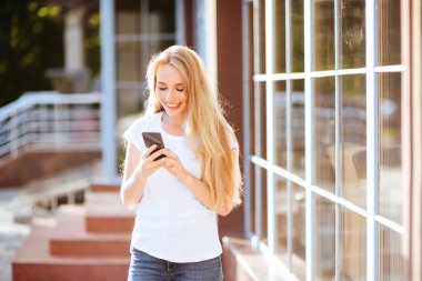 Açık havada Smartphone kullanarak çekici gülümseyen kadın.