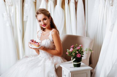 Çekici genç gelin modern düğün salonu gelinlik seçerken gülümsüyor