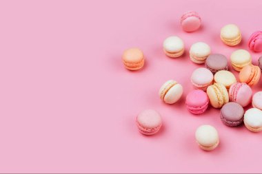 Macaroons pembe bir arka plan üzerinde farklı türleri. Tatlı ve renkli Fransızca macaroons.