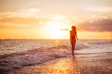 Sahilde gün batımında dans eden kaygısız bir kadın. Tatil canlılığı sağlıklı yaşam konsepti