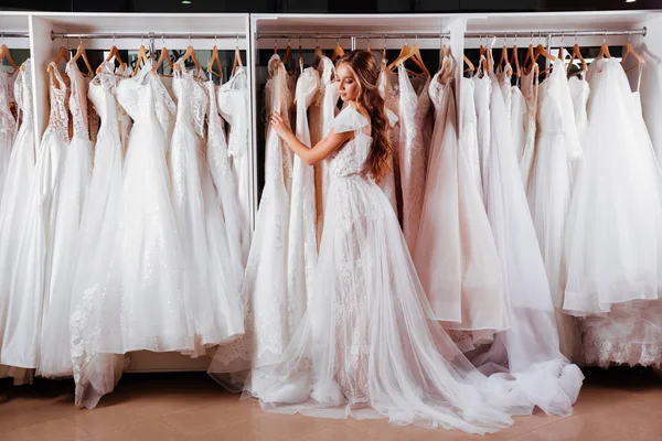 美しい花嫁は モダンなウェディング サロンで優雅なウェディング ドレスを試着します — ストック写真