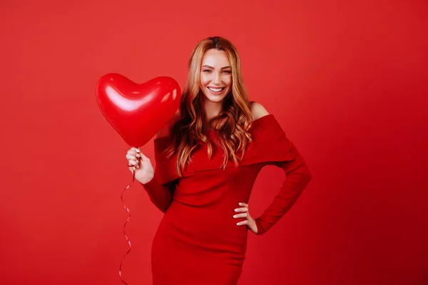 Joven chica encantadora con el pelo largo y rizado, en vestido rojo sosteniendo globos de aire, posando en la cámara . — Foto de Stock