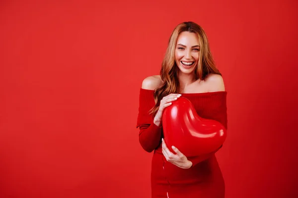 Joven chica encantadora con el pelo largo y rizado, en vestido rojo sosteniendo globos de aire, posando en la cámara . — Foto de Stock