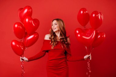 Hava balonları, holding kırmızı elbiseli uzun kıvırcık saçlı genç çekici kız kameraya poz.