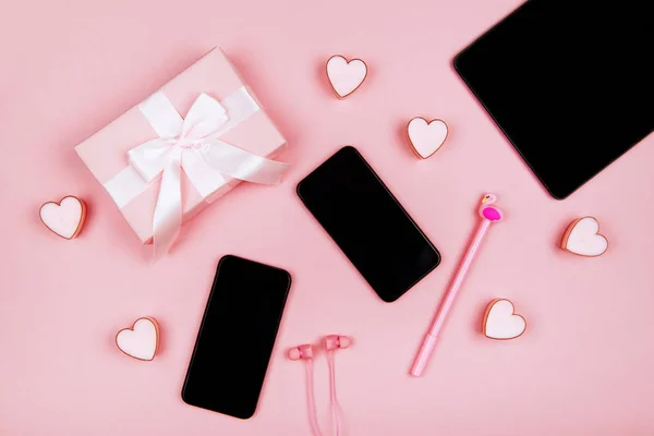 Смартфон, ноутбук, подарунки, навушники та жіночі аксесуари на рожевому фоні — стокове фото