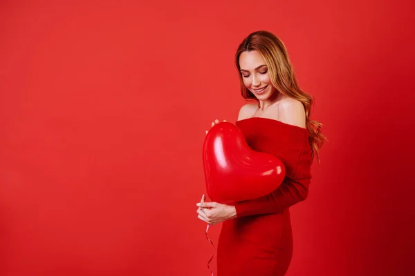 Joven chica encantadora con el pelo largo y rizado, en vestido rojo sosteniendo globos de aire, posando en la cámara . — Foto de Stock