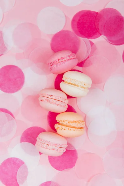 Macarons colorés savoureux sur papier rose pastel tendance avec confettis . — Photo