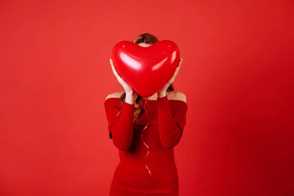 Joven chica encantadora con el pelo largo y rizado, en vestido rojo sosteniendo globos de aire, posando en la cámara . — Foto de Stock