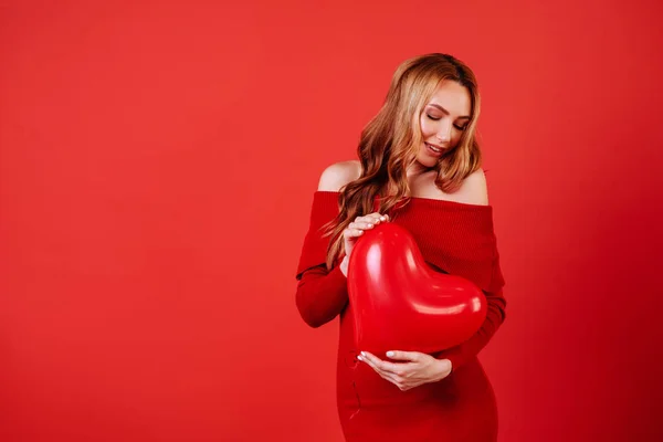 Joven chica encantadora con el pelo largo y rizado, en vestido rojo sosteniendo globos de aire, posando en la cámara . — Foto de Stock