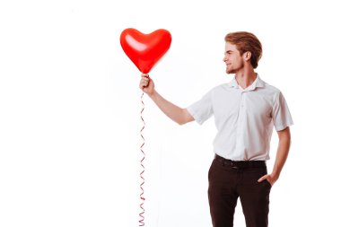 Kırmızı bir kalp tutan genç gülümseyen bir adam portresi tam uzunlukta balon şeklinde
