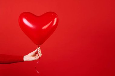 Bir kırmızı kalp balon tutan el