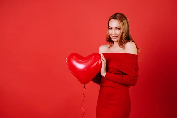 Joven chica encantadora con el pelo largo y rizado, en vestido rojo sosteniendo globos de aire, posando en la cámara . — Foto de Stock