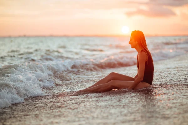 Silhouette eines Mädchens im Wasser bei Sonnenuntergang. — Stockfoto