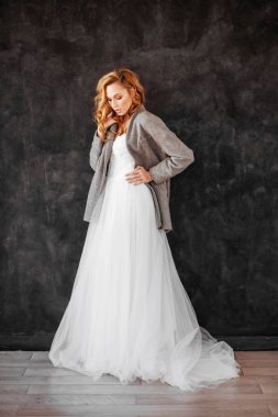 Gülümseyen güzel sarışın kadın modeli şık karanlık palto ve beyaz elbise