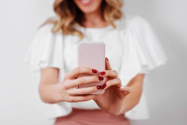 Elinde akıllı telefon tutan gülümseyen sıradan bir kadının portresi.