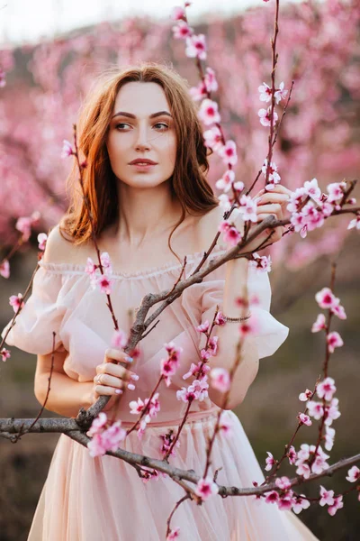 Piękna młoda dziewczyna pod kwitnącym różowym drzewem — Zdjęcie stockowe
