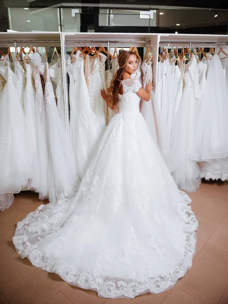 Visão traseira de uma jovem mulher em vestido de noiva olhando para vestidos de noiva — Fotografia de Stock