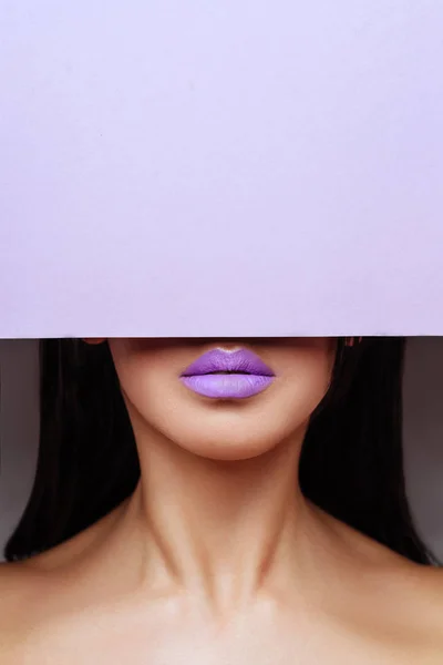 Яскраво-фіолетові губи дивиться в отвір кольорового паперу . — стокове фото