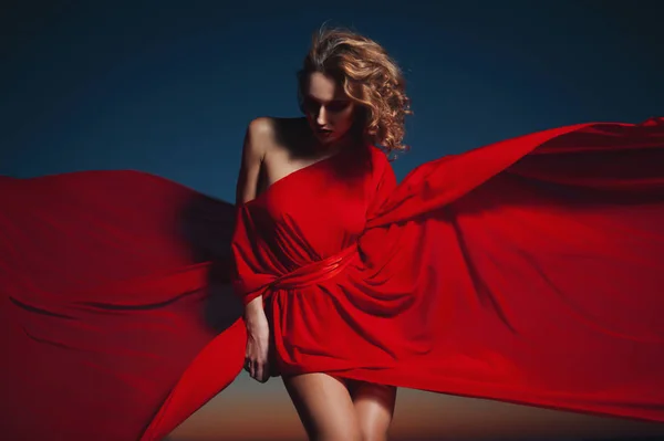 Žena tančí v hedvábných šatech, umělecké červené foukání šaty mávání a letící tkaniny — Stock fotografie