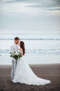 Gün batımı sırasında okyanus plajında yürüyüş zarif muhteşem gelin ve damat.