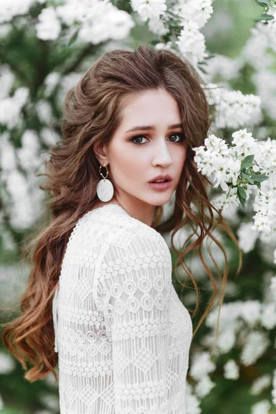 Una hermosa joven se encuentra entre los árboles florecientes . — Foto de Stock