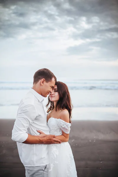 Elegant gorgeous bride and groom walking on ocean beach during sunset time. — Stock Photo, Image