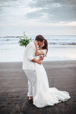 Gün batımı sırasında okyanus plajında yürüyüş zarif muhteşem gelin ve damat.