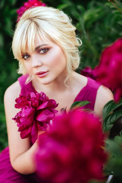 Outdoor close up portrait of beautiful young woman in the blooming garden. Female spring fashion concept