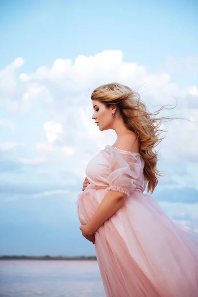 Hermosa joven embarazada disfrutando del sol en el lago rosa — Foto de Stock