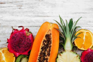 Tropikal meyveler ahşap beyaz yüzeyde yatıyor.