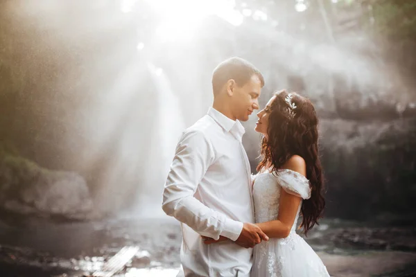 Pareja joven enamorada novia y novio, día de la boda cerca de una cascada de montaña . —  Fotos de Stock