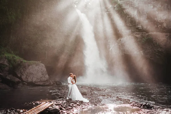 Mladý pár v lásce nevěsta a ženich, svatební den u horského vodopádu. — Stock fotografie