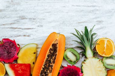 Tropikal meyveler ahşap beyaz yüzeyde yatıyor.