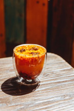 Taze deniz dikeni çilek ve yaprakları ile bir cam bardak portakal ile deniz dikeni çay.