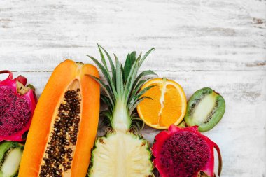 Tropikal meyveler ahşap beyaz yüzeyde yatıyor.