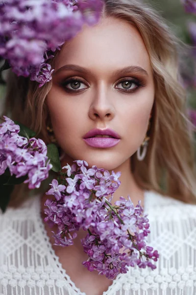 Belle femme appréciant le jardin lilas, jeune femme avec des fleurs dans le parc vert . — Photo