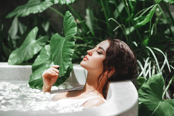 Femme relaxante dans un bain extérieur rond avec des fleurs tropicales . — Photo