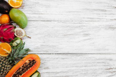 Tropikal meyveler ahşap beyaz yüzeyde yatıyor.