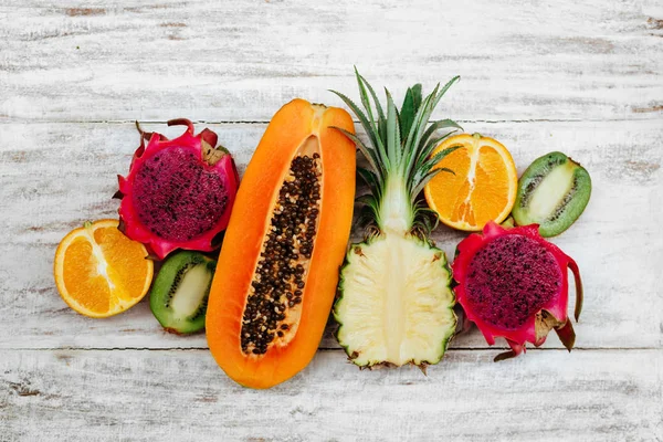 Tropische Früchte liegen auf einer hölzernen weißen Oberfläche. — Stockfoto