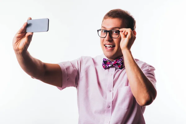 Retrato de un joven guapo, sosteniendo un smartphone, mirando a la cámara y riendo — Foto de Stock
