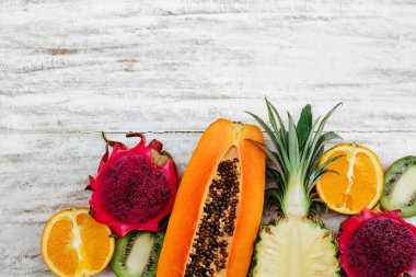 Tropikal meyveler ahşap beyaz yüzeyde yatıyor.