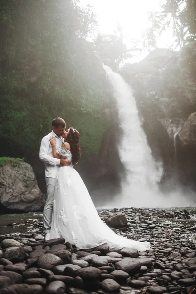 Young couple in love bride and groom, wedding day near a mountain waterfall. — Stock Photo, Image