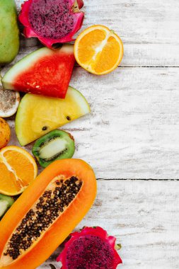 Tropikal meyveler ahşap beyaz yüzeyde yatıyor.