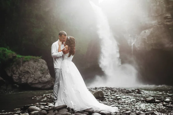 Pareja joven enamorada novia y novio, día de la boda cerca de una cascada de montaña . —  Fotos de Stock