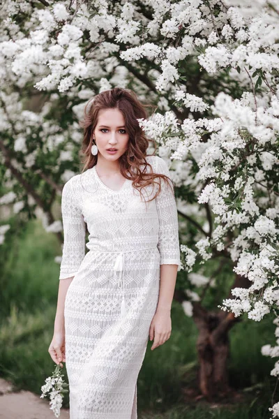 Una hermosa joven se encuentra entre los árboles florecientes . — Foto de Stock