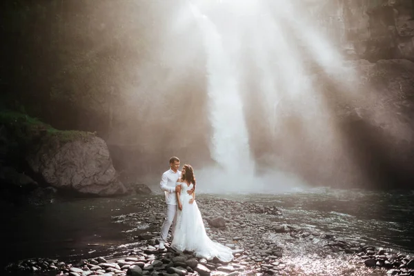 Pareja joven enamorada novia y novio, día de la boda cerca de una cascada de montaña . —  Fotos de Stock